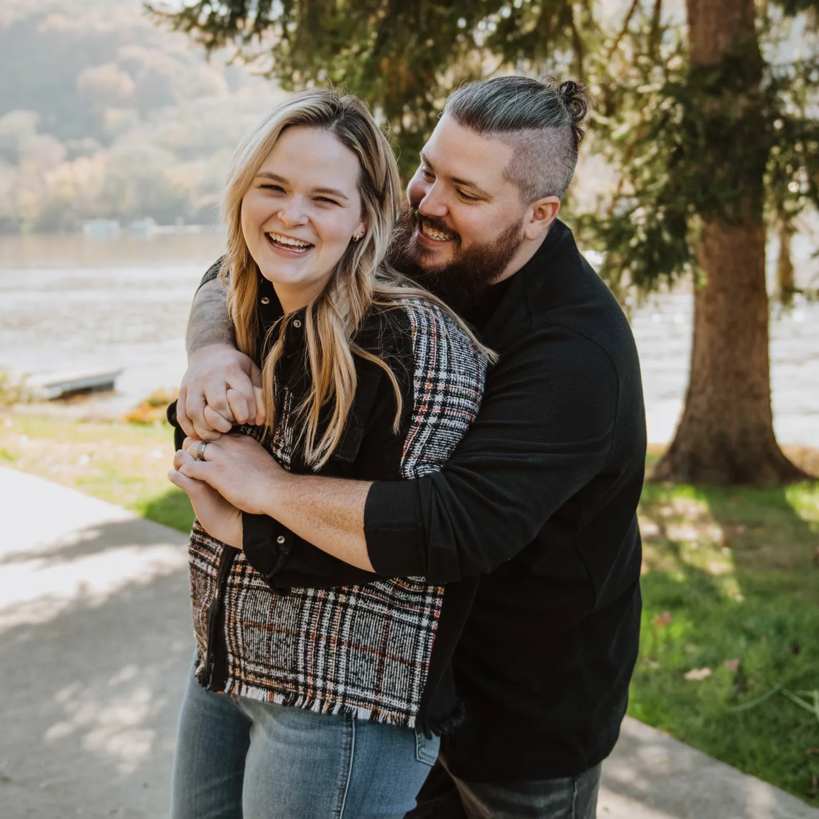 Taylor Hiott smiling with his wife, Brooke, beside the river.