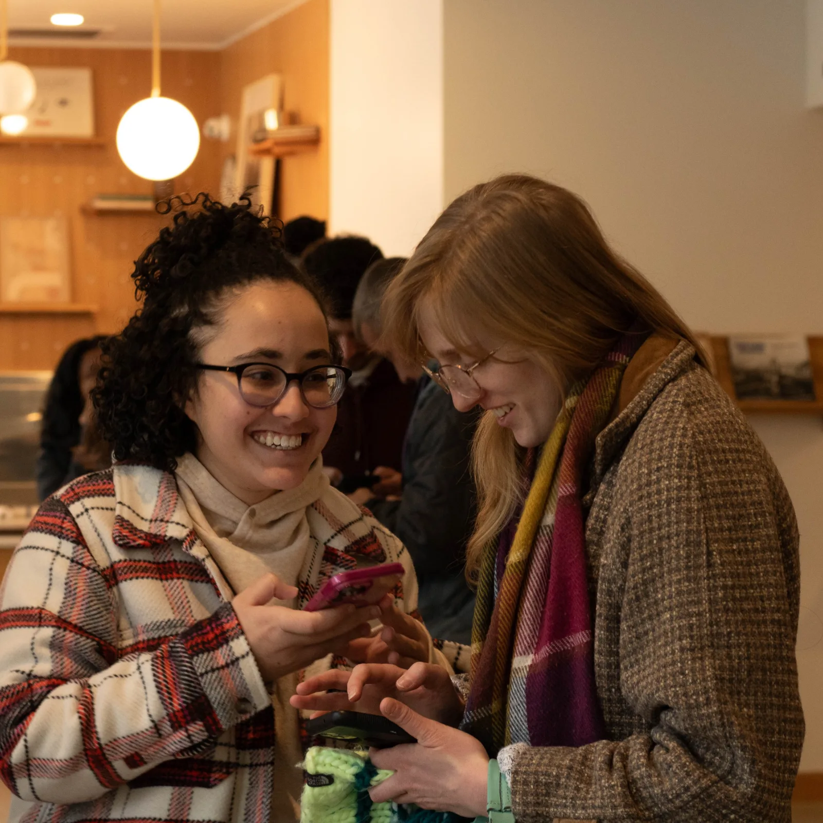 Two friends laugh together while looking at a phone in The Sanctuary lobby.