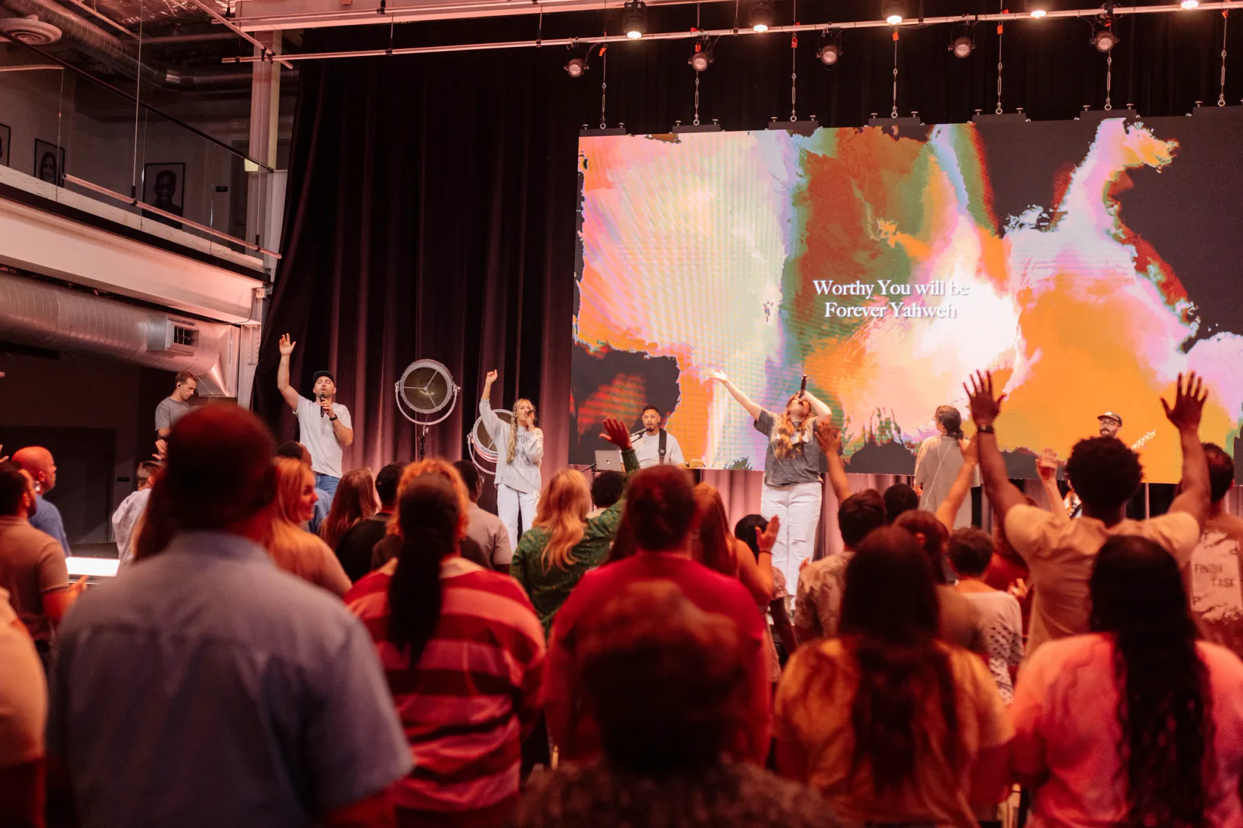 A Sanctuary gathering worships together as musicians lead from the stage.